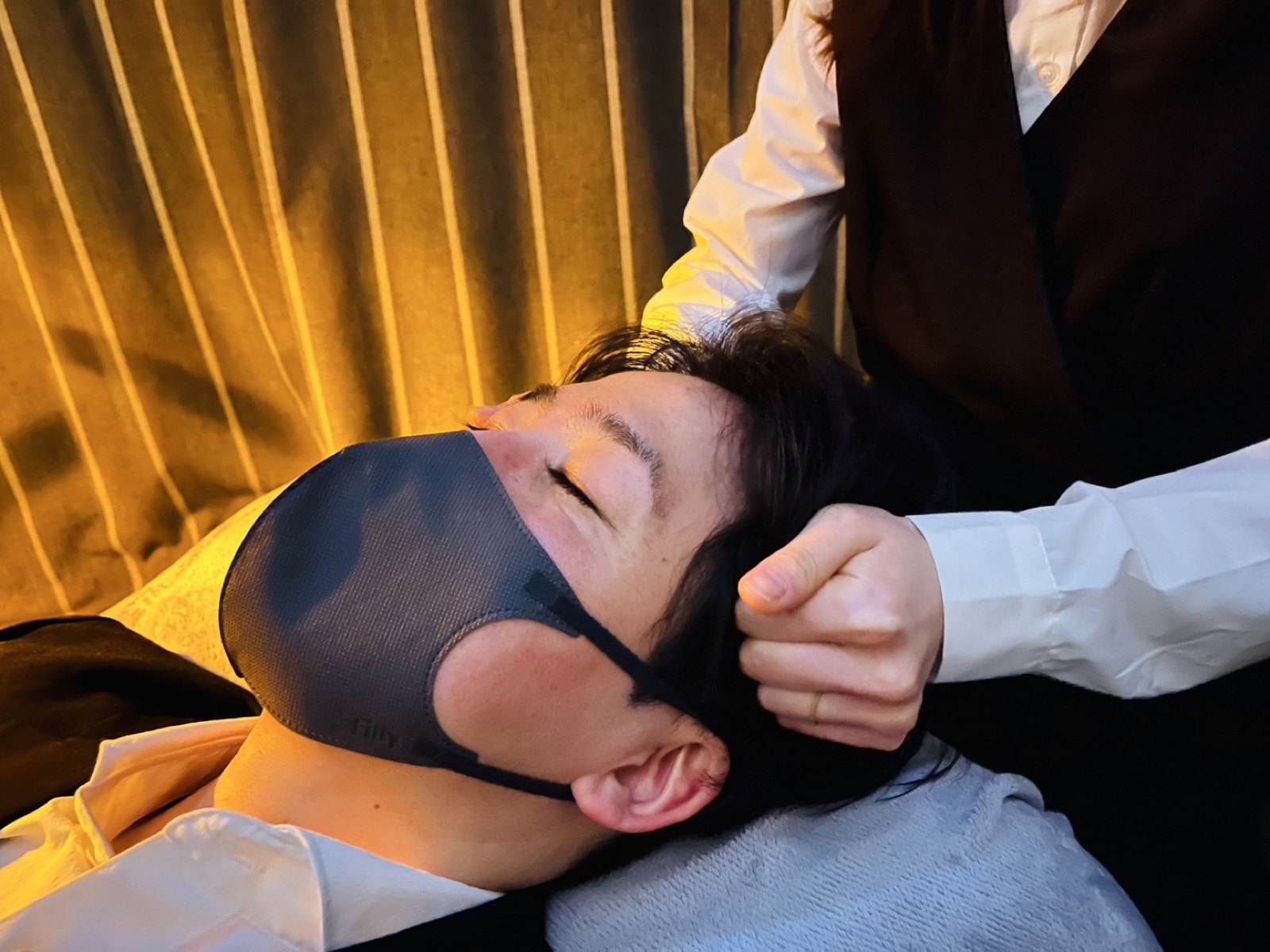 目を閉じてドライヘッドスパを受ける男性のお客様